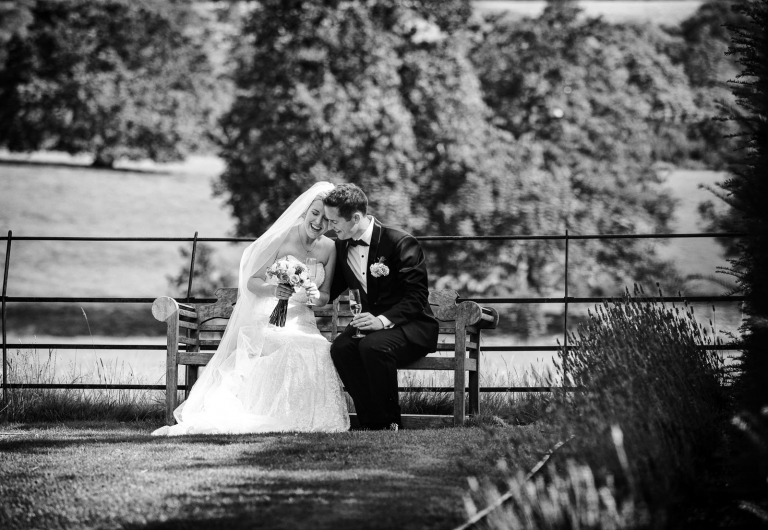 bride and groom taking a moment together on the bench at wadhurst castle