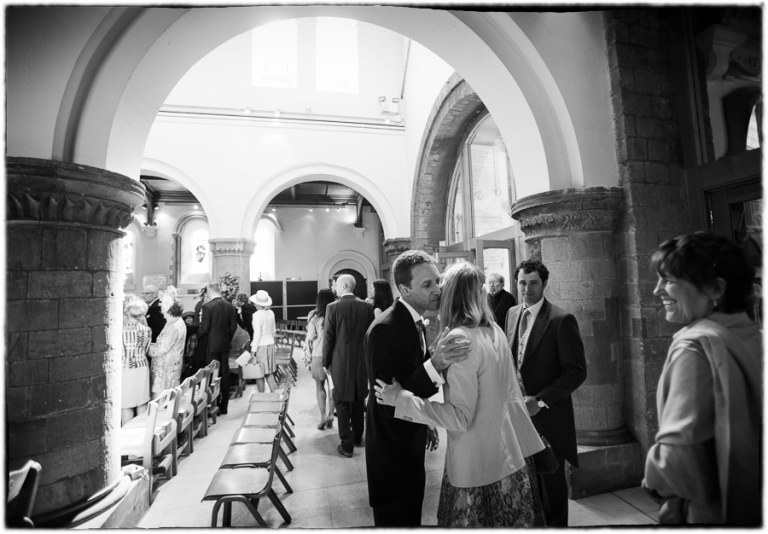 the groom greeting guests at St Peter's church in Petersfield