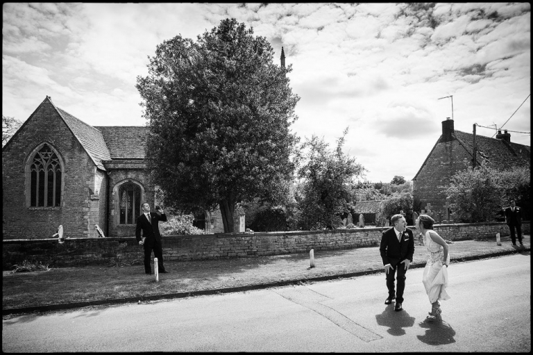 A storytelling wedding image showing the bride and groom laughing at each other outside the church