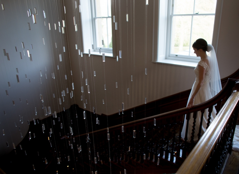 bride coming down the stairs for her wedding ceremony at cowley manor