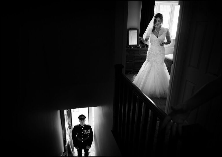 documentary wedding photograph showing the brides father at the front door while the bride gets ready upstairs. 