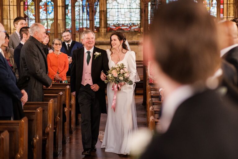 The bride walking up the aisle for her wedding at St Etheldreda's church 